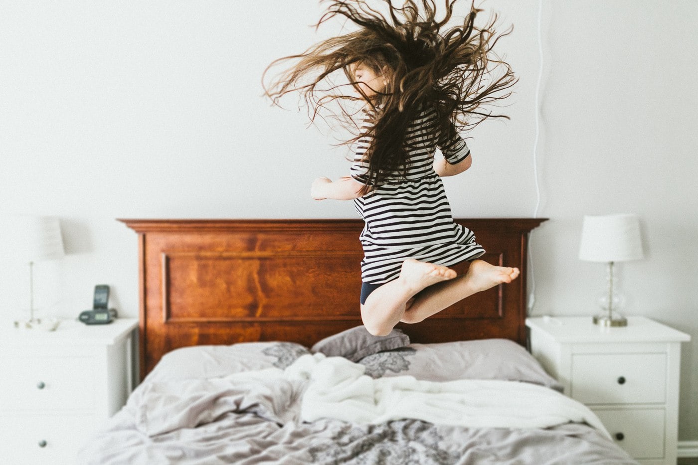 girl jumping on bed