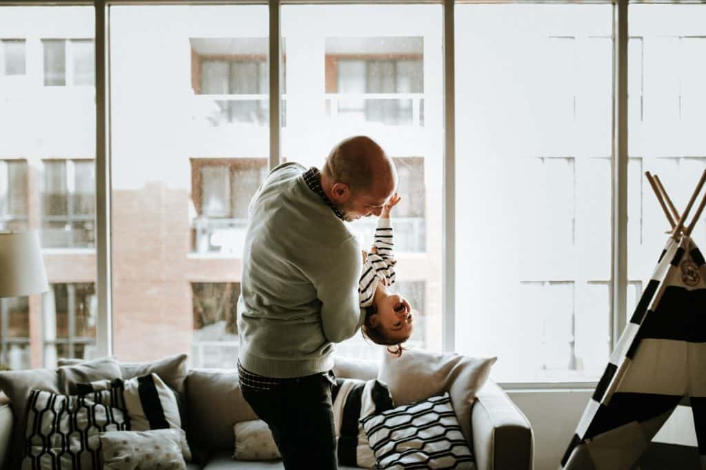 man playing with son in their home
