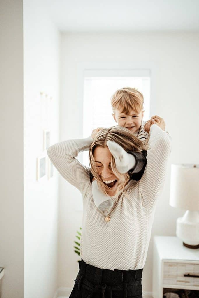 Woman laughing with her young son sitting on her shoulders
