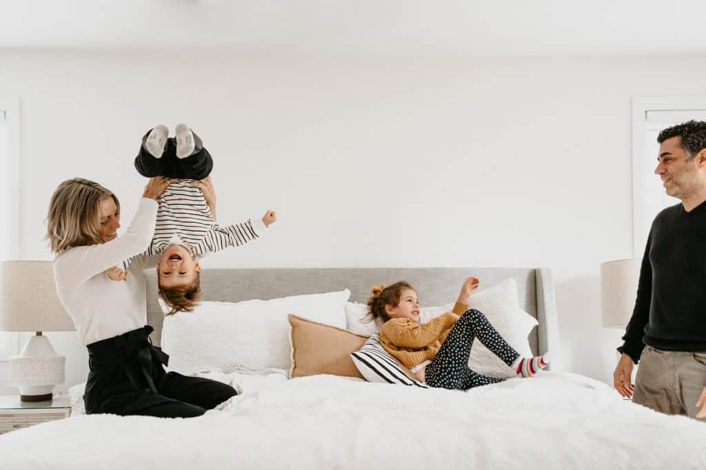 Family on bed playing with children laughing