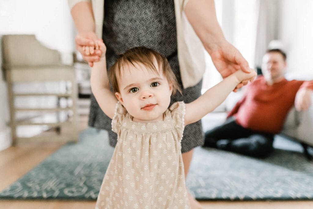 Baby girl learning to walk holding mom's hands