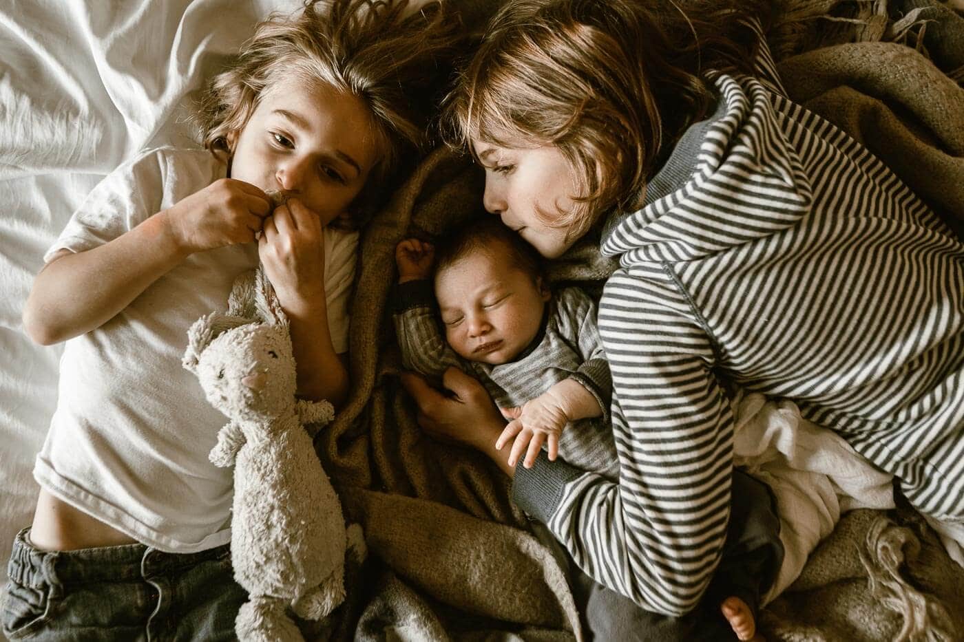 new mom and dad lying on bed with newborn baby