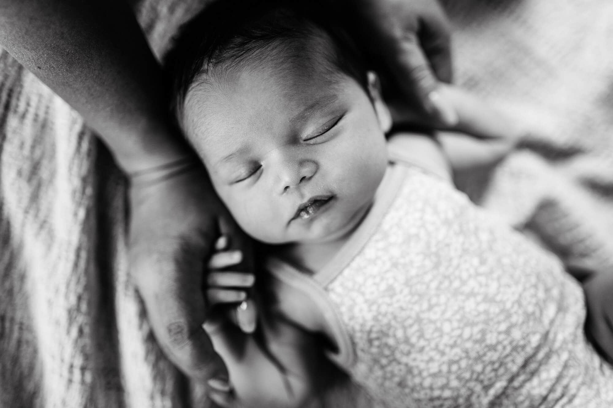 new mom and dad lying on bed with newborn baby