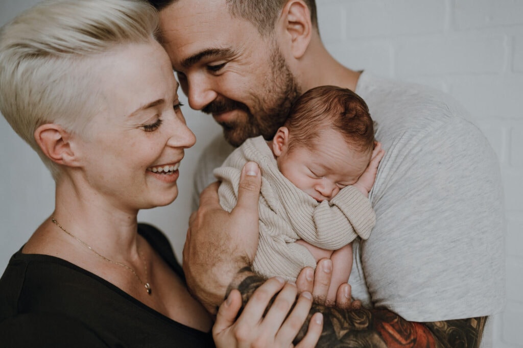 mom and dad smiling holding newborn baby boy