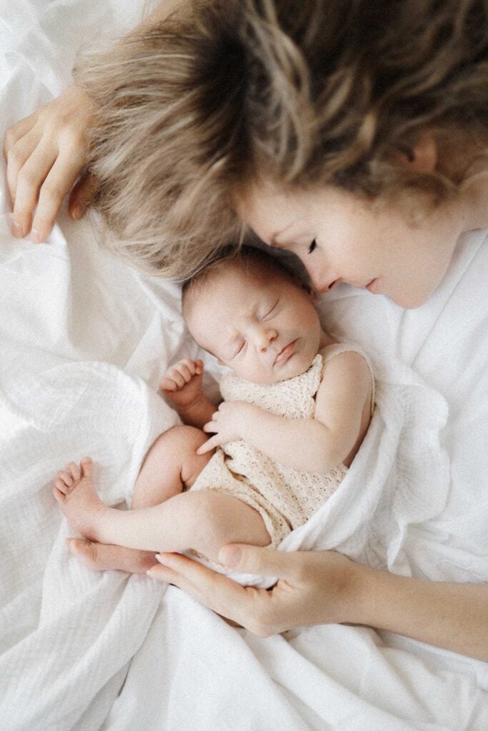 Newborn baby lying down on bed with her mom