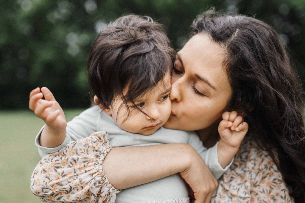 mom kisses little girl on the cheek outside by montreal family photographer Carolina Hanna