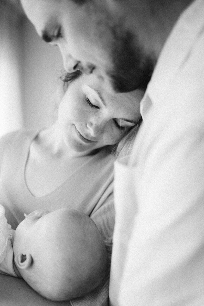 Professional newborn photography in Montreal in-home with natural light - mom and dad holding baby close.