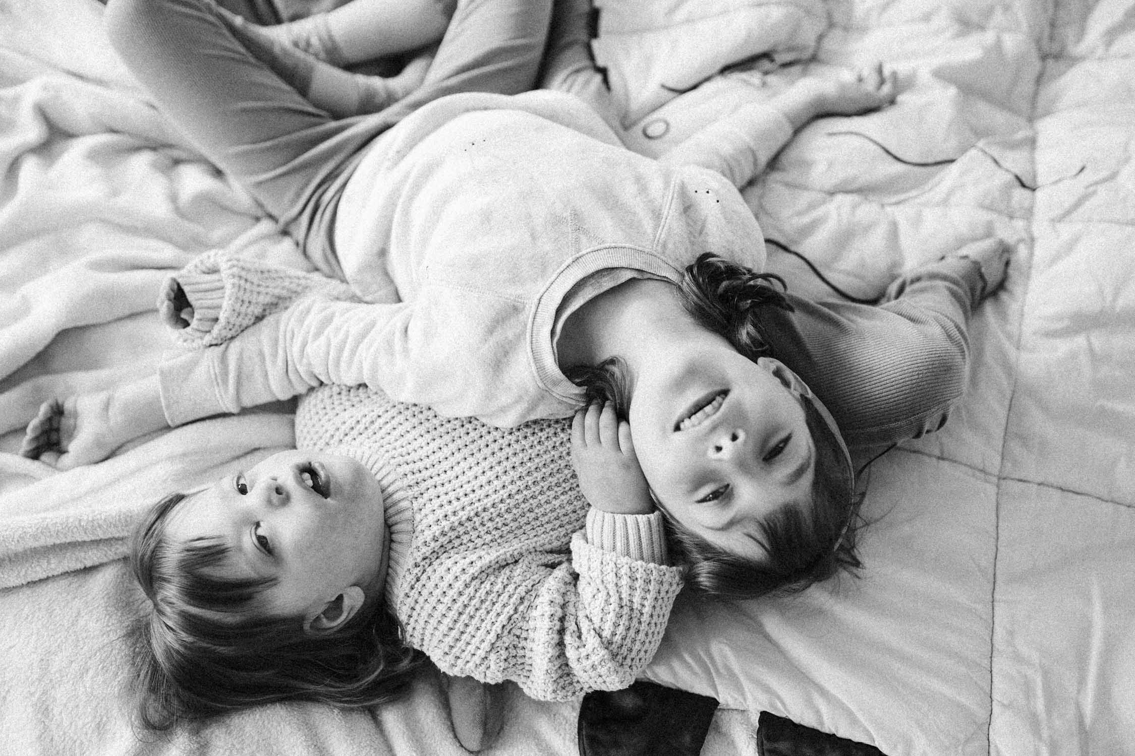 Sisters laying on each other in their bed during their in-home family photo session in Montreal