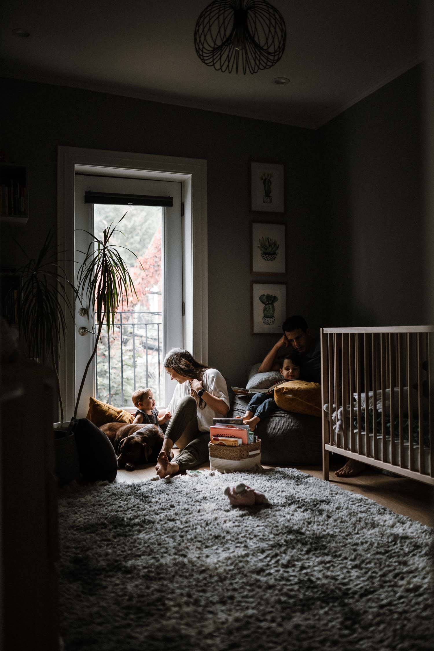 family sits and plays by the window in child's bedroom