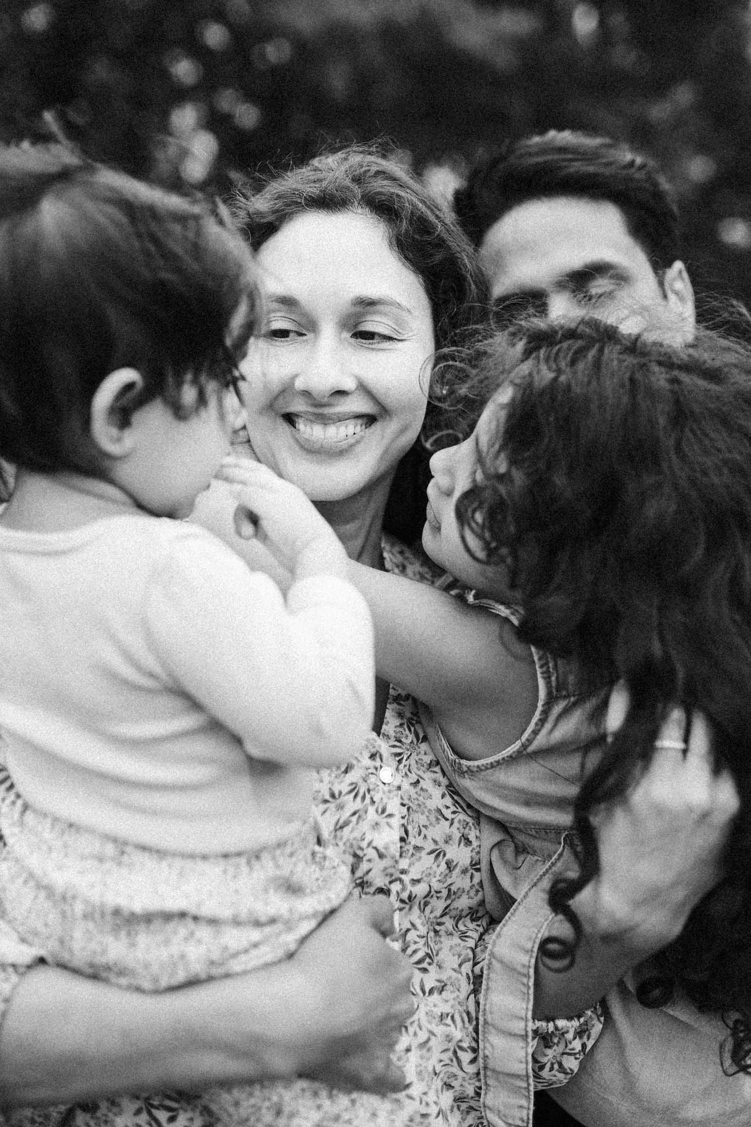 mom smiles as her little girls hug her