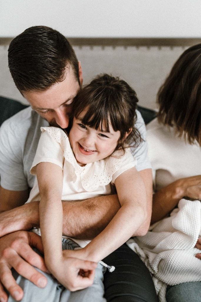 Dad cuddles his oldest daughter during family photoshoot at home in montreal