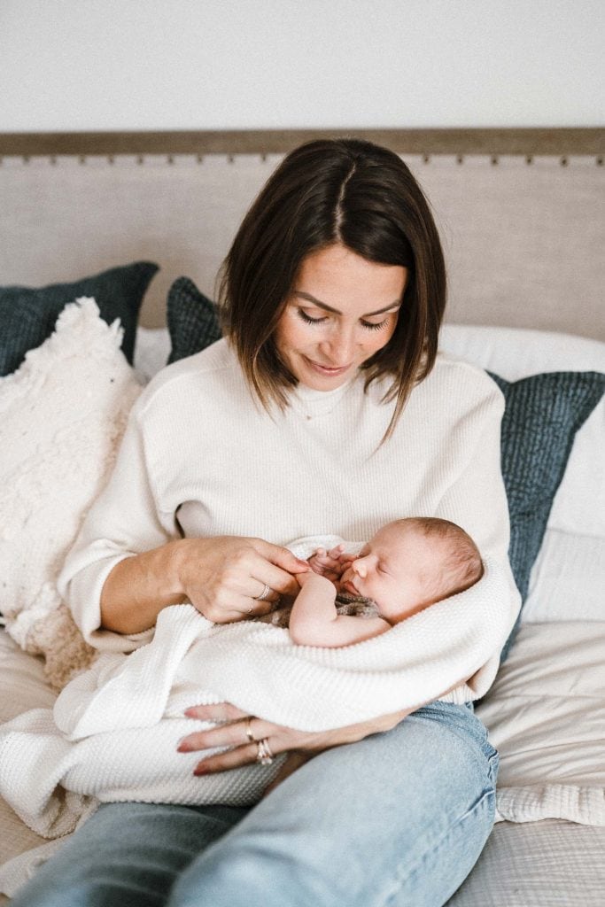 Mother holding newborn baby girl during in-home family photoshoot in Montreal.