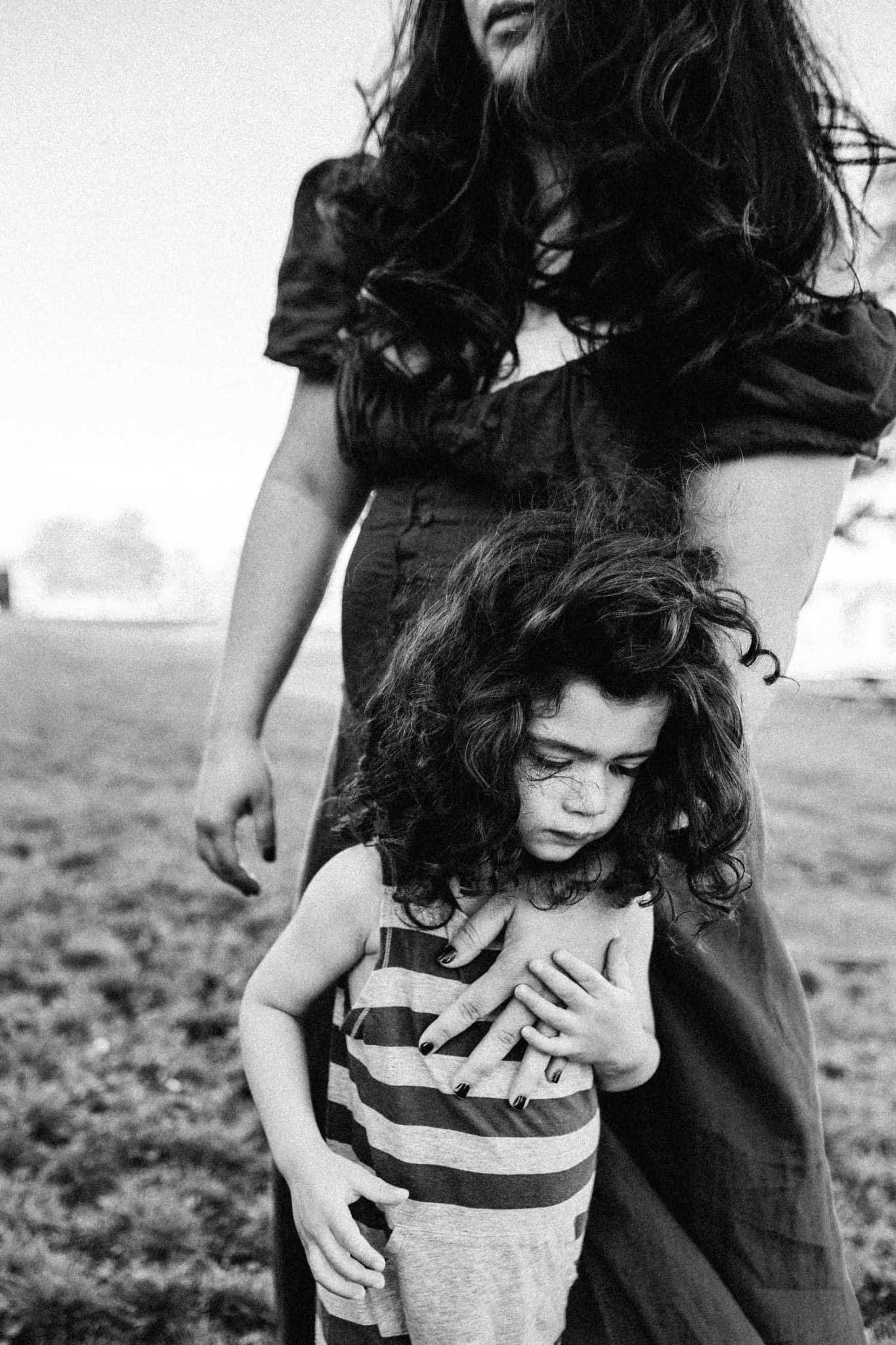 Mother and son, boy holds mom as she looks into the distance in black and white old port montreal