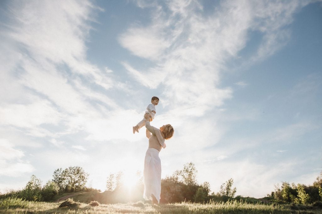 mom holds little boy up in the air during outdoor family photo shoot in montreal
