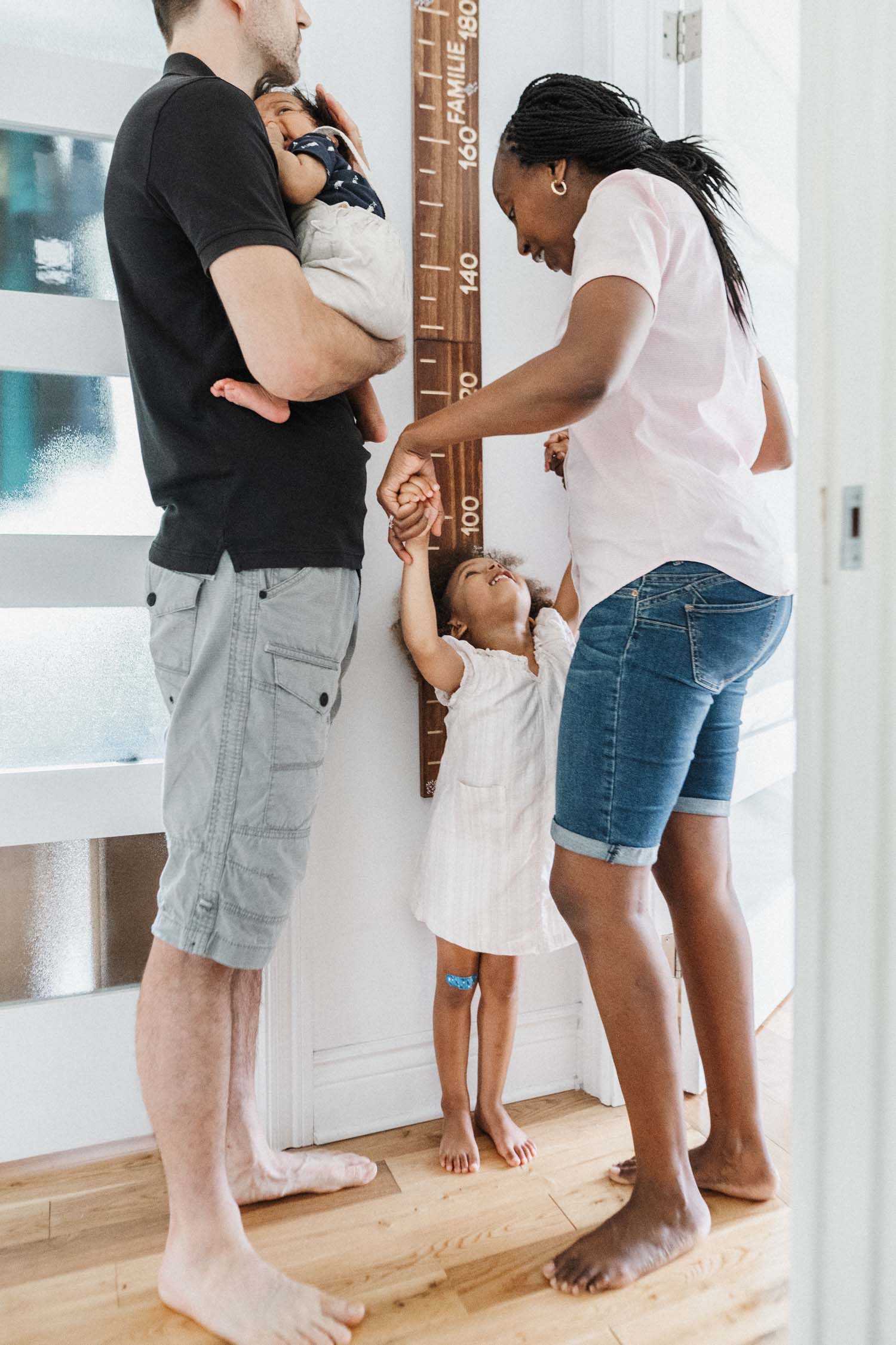 Mom measure daughter on the wall during their at-home family photo session in Montreal