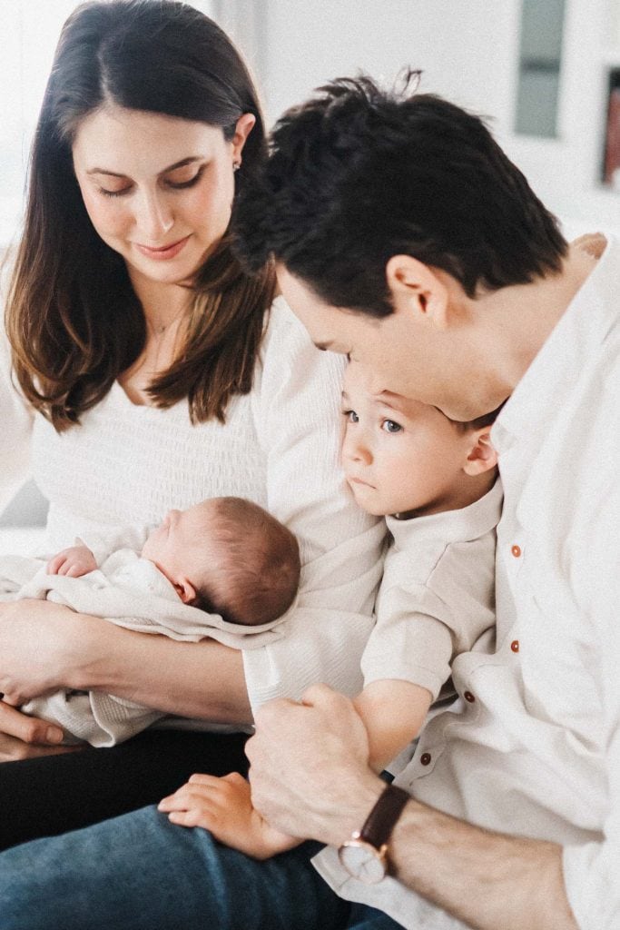 mom holds baby while dad wrangles older brother