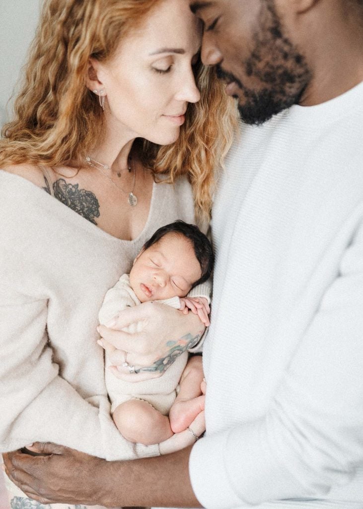 new parents holding newborn daughter during in-home baby photoshoot in montreal