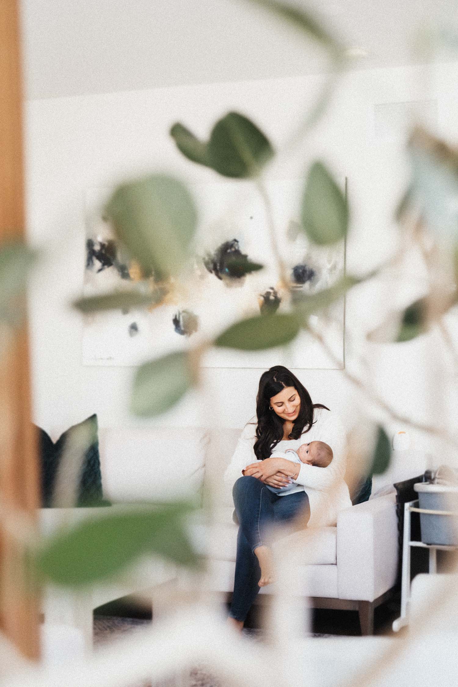 mom holding baby as seen in mirror reflection during in home newborn photoshoot