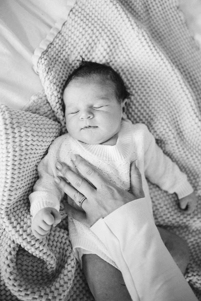 Close up of newborn baby with mom's hand on her baby's chest during their in-home family photo shoot