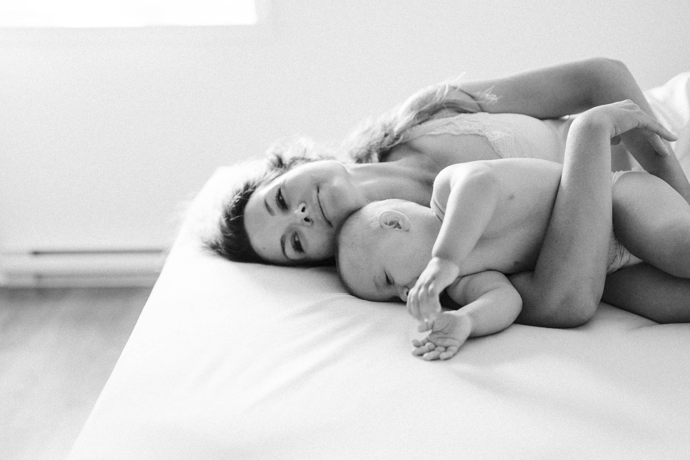 black and white photo of mother embracing her baby on the bed at home during their montreal area family photo shoot
