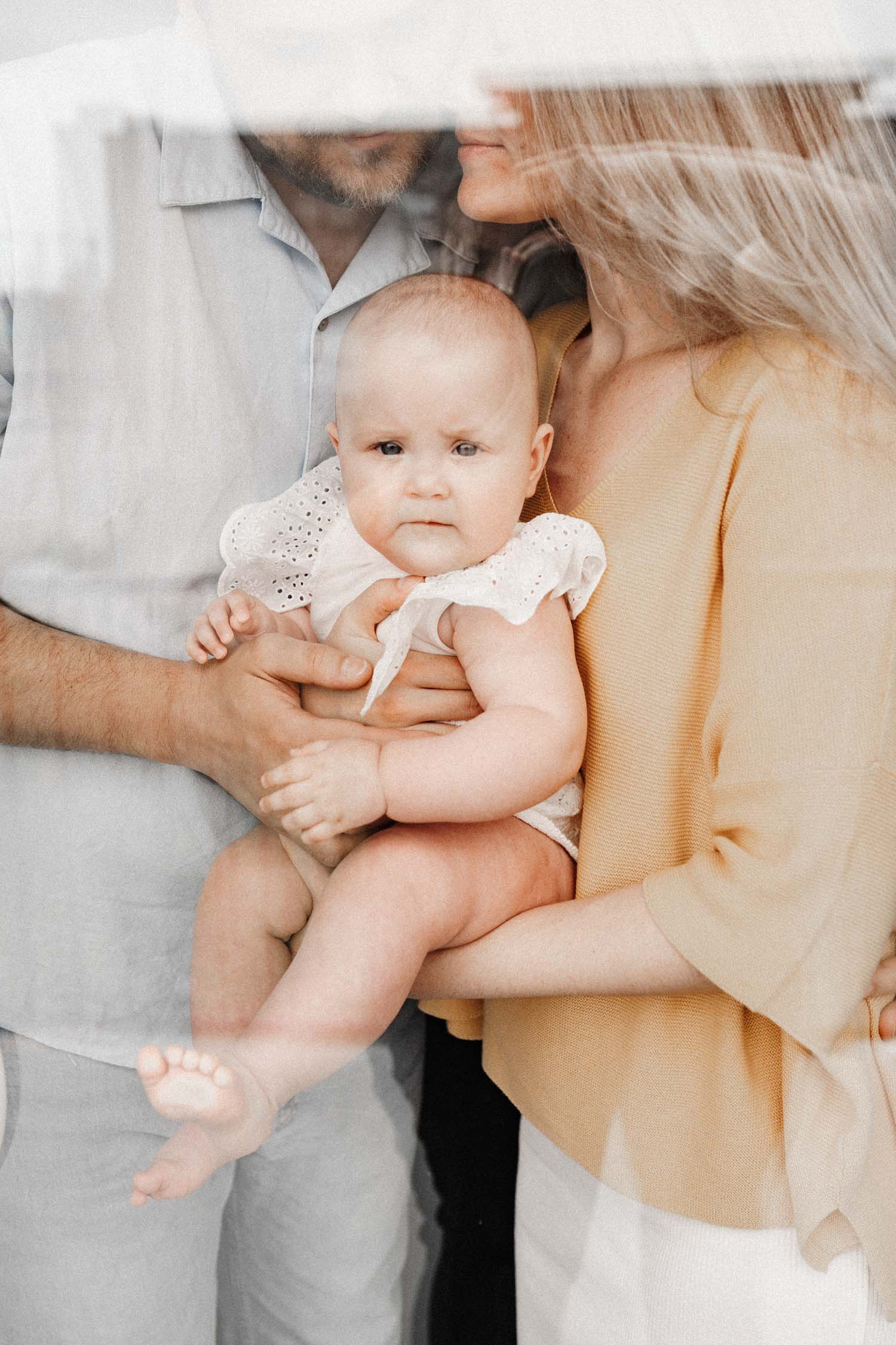 Couple holds their baby cuddled close during their in-home family photo session in Montreal