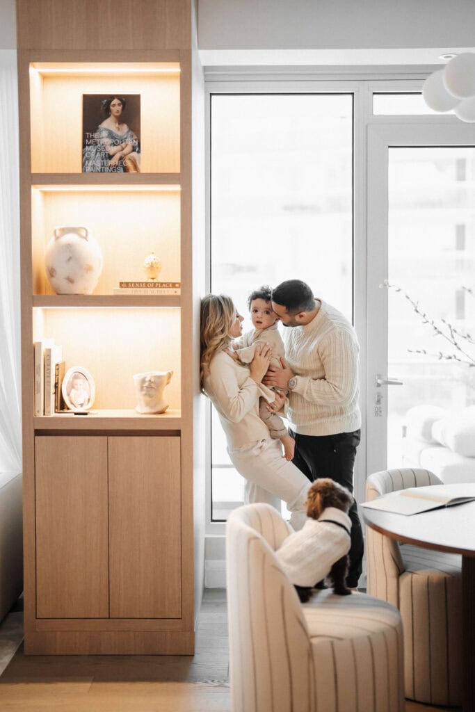 A family enjoys time in their living room, with a dog resting comfortably on the chair nearby during Montreal Family Photoshoot