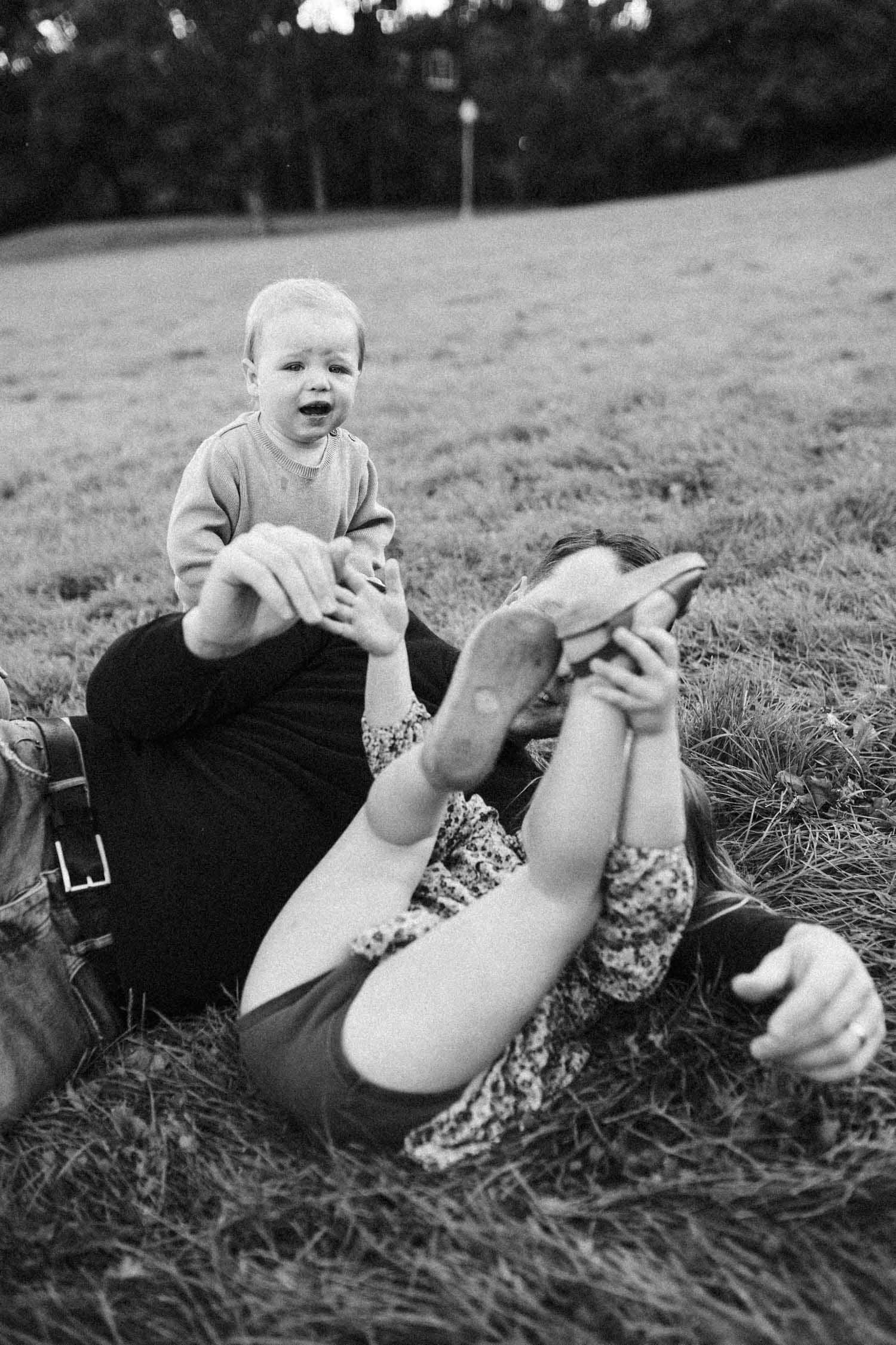 Dad and kids rolling around in the grass during their outdoor family photoshoot in MOntreal