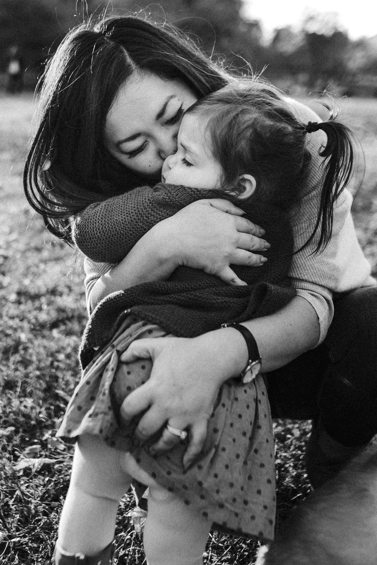 Mom and daughter hug outside in a park in montreal during their fall family photo shoot